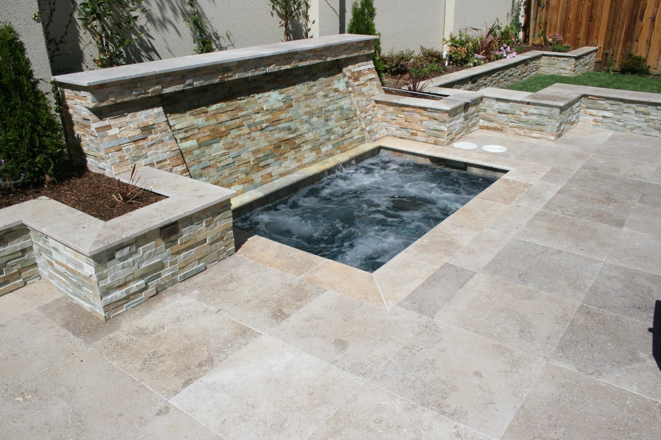 Small backyard pool with stone waterfall