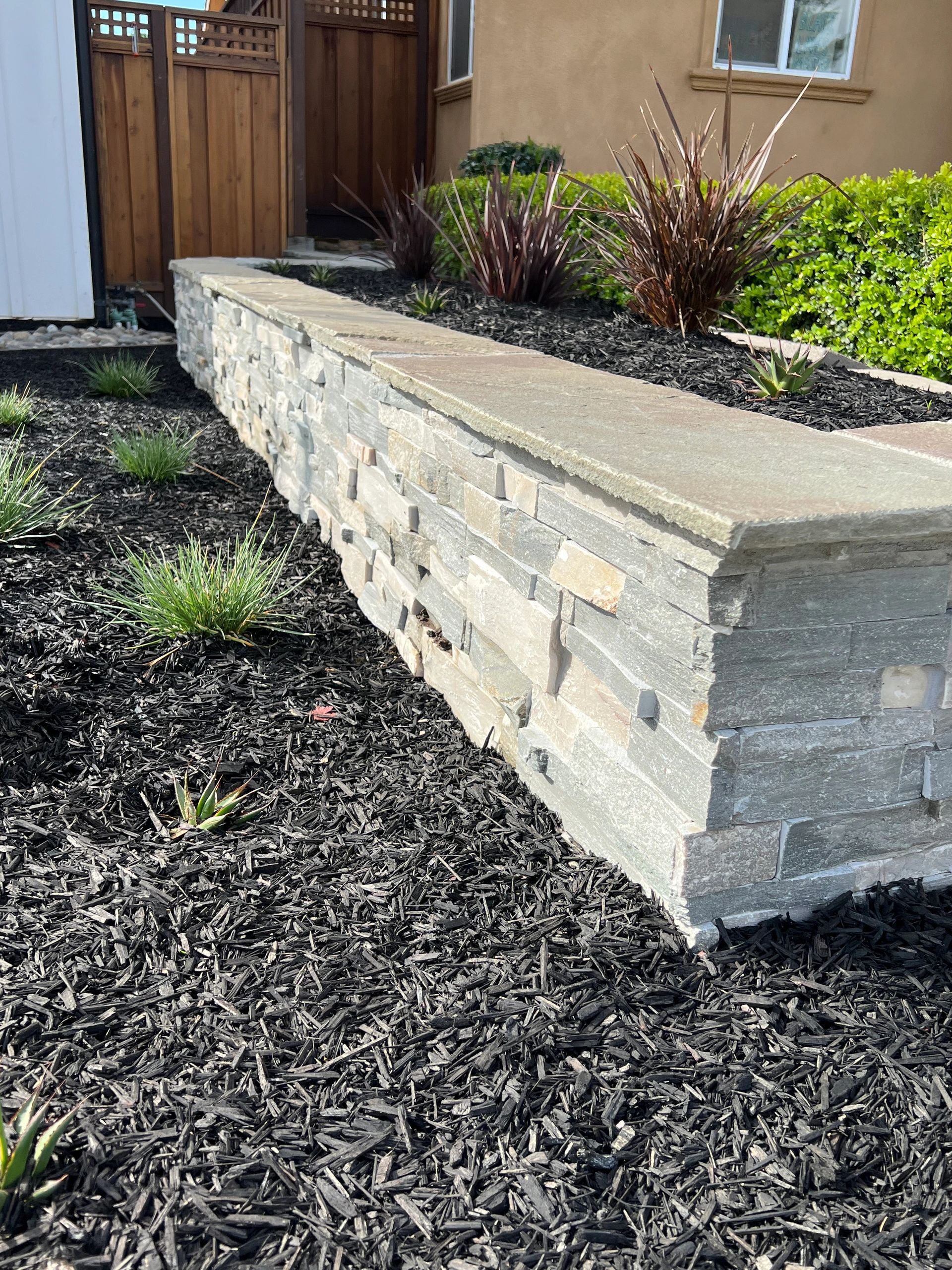 Stone retaining wall with mulch landscaping.