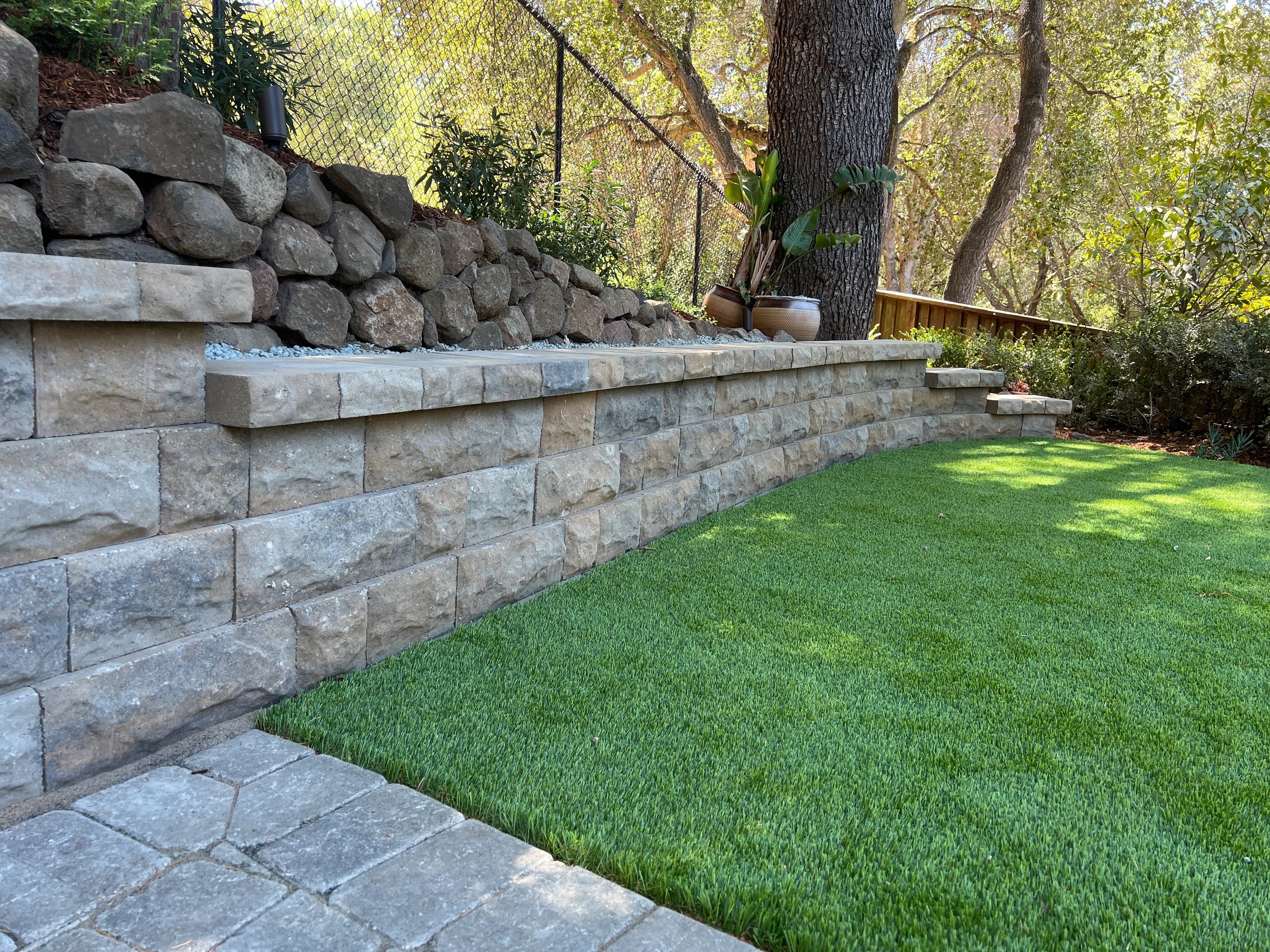 Stone retaining wall with lush green grass.