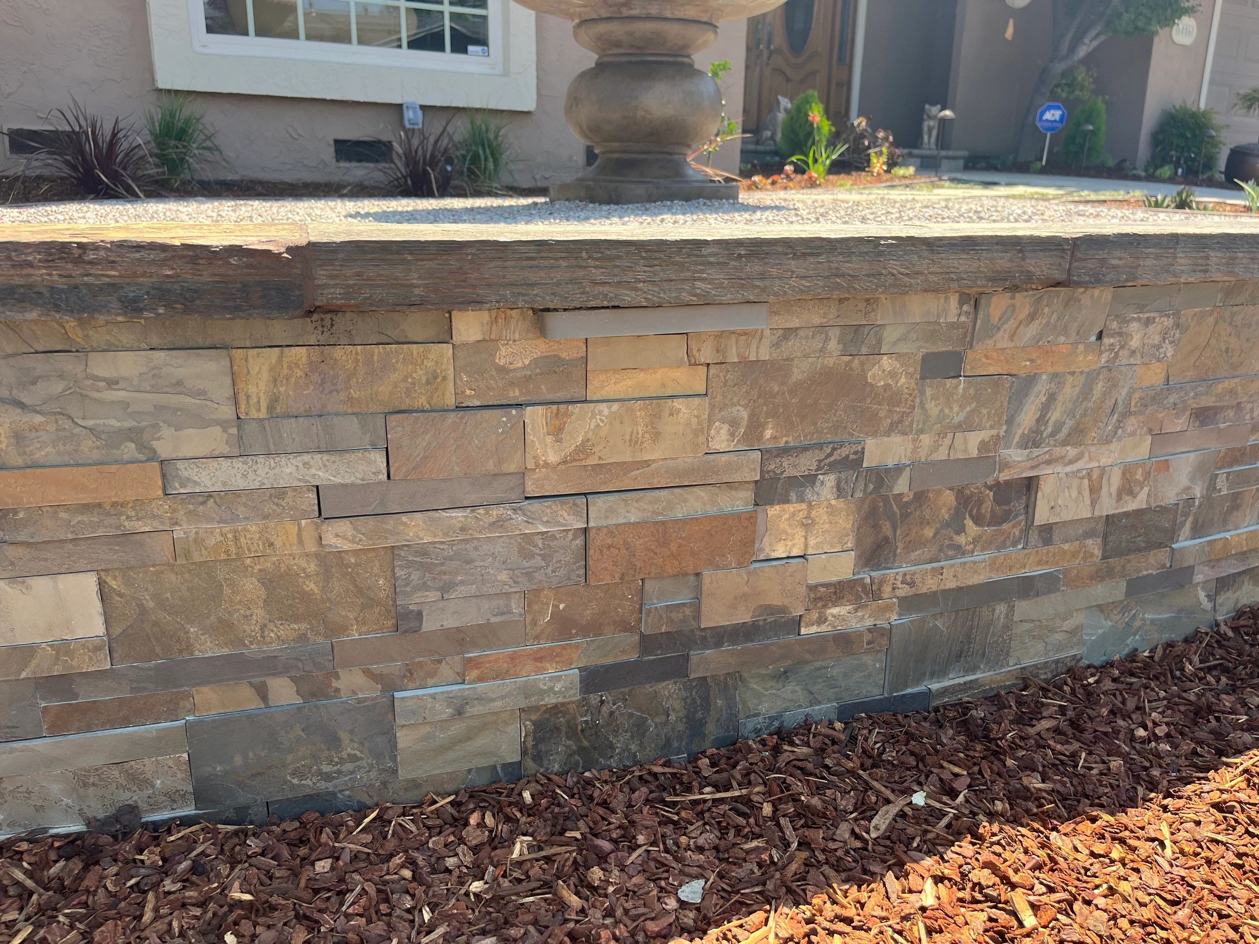 Stone veneer wall with mulch foreground