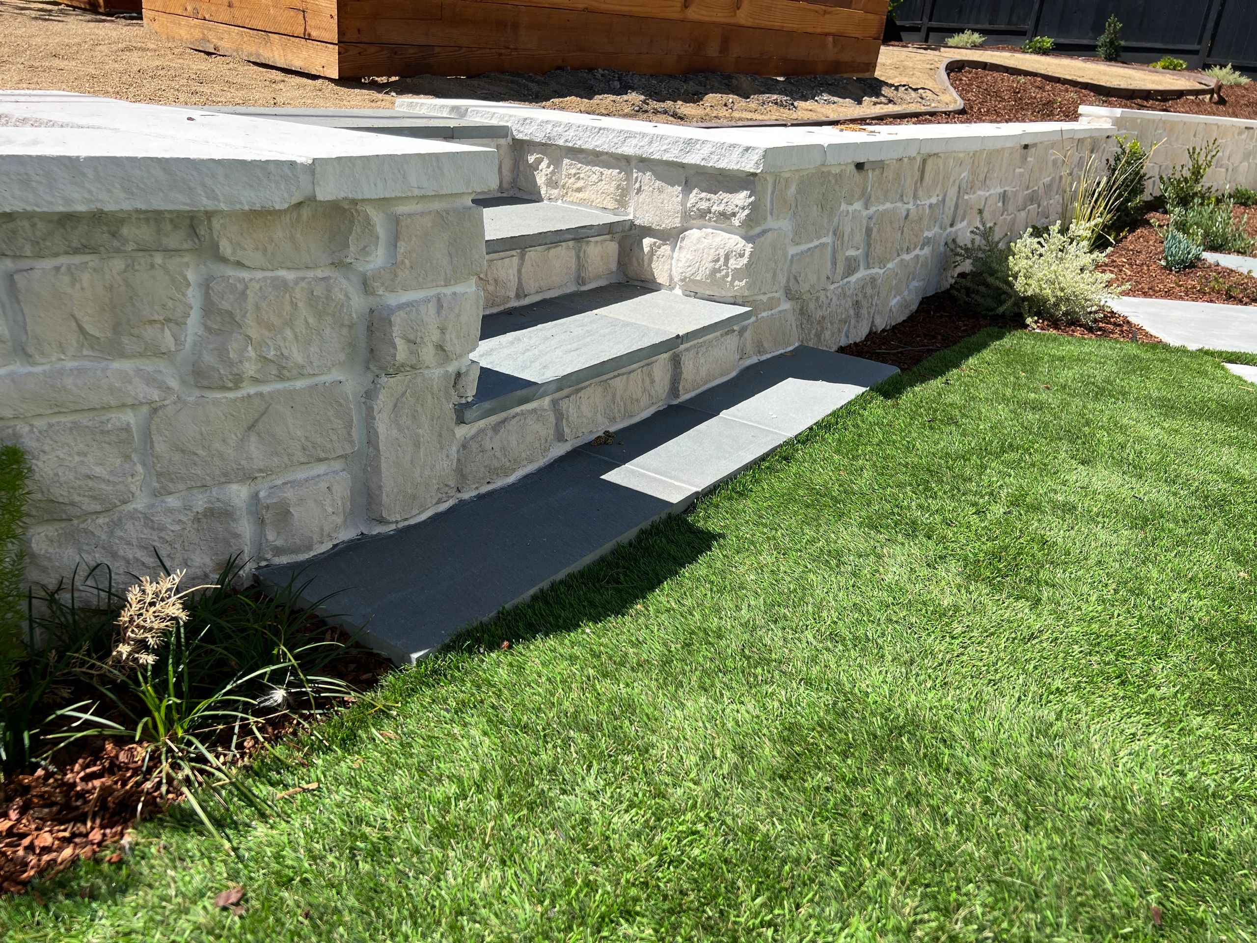 Grass lawn with stone steps and wall