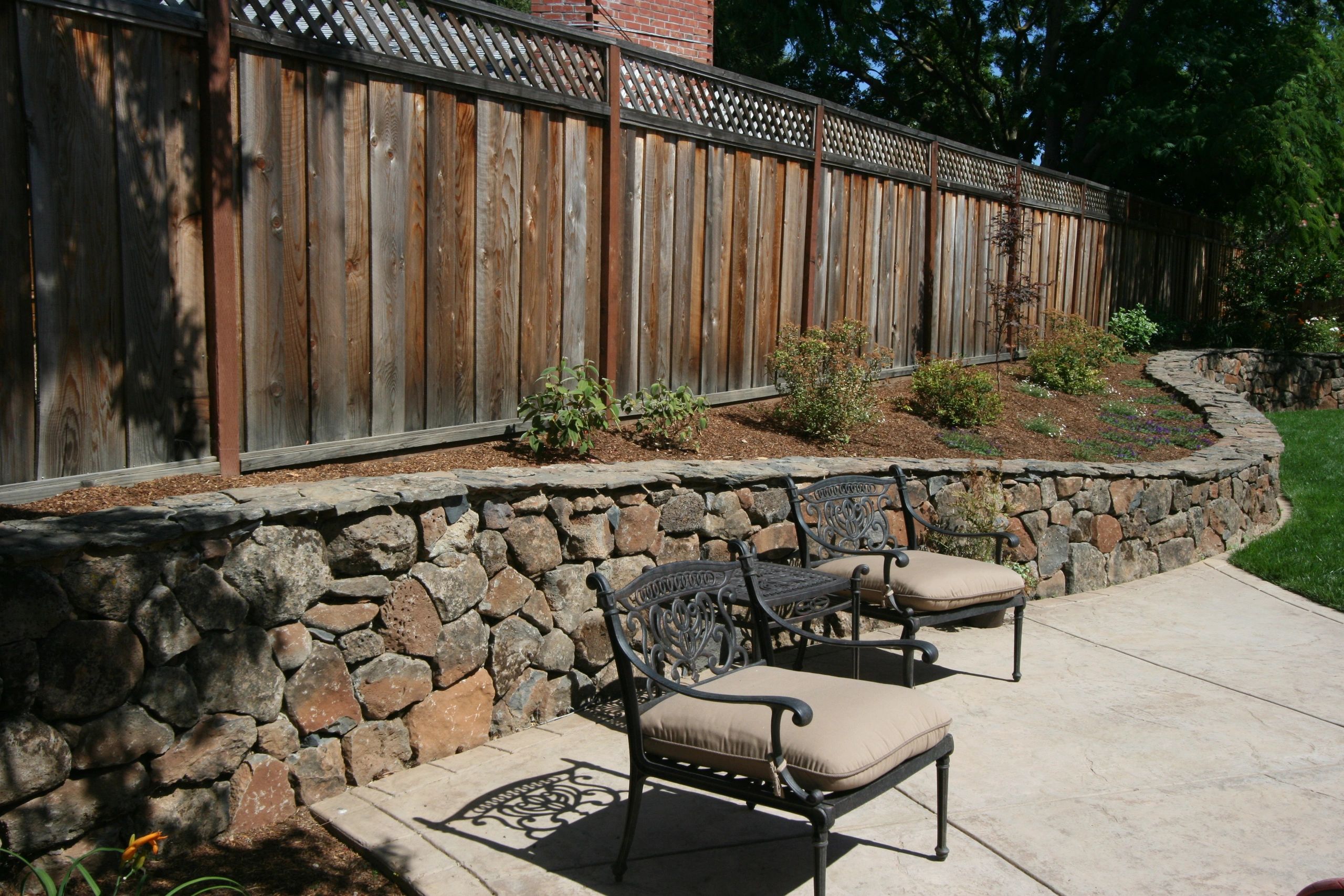 Outdoor patio with decorative chairs and fence.