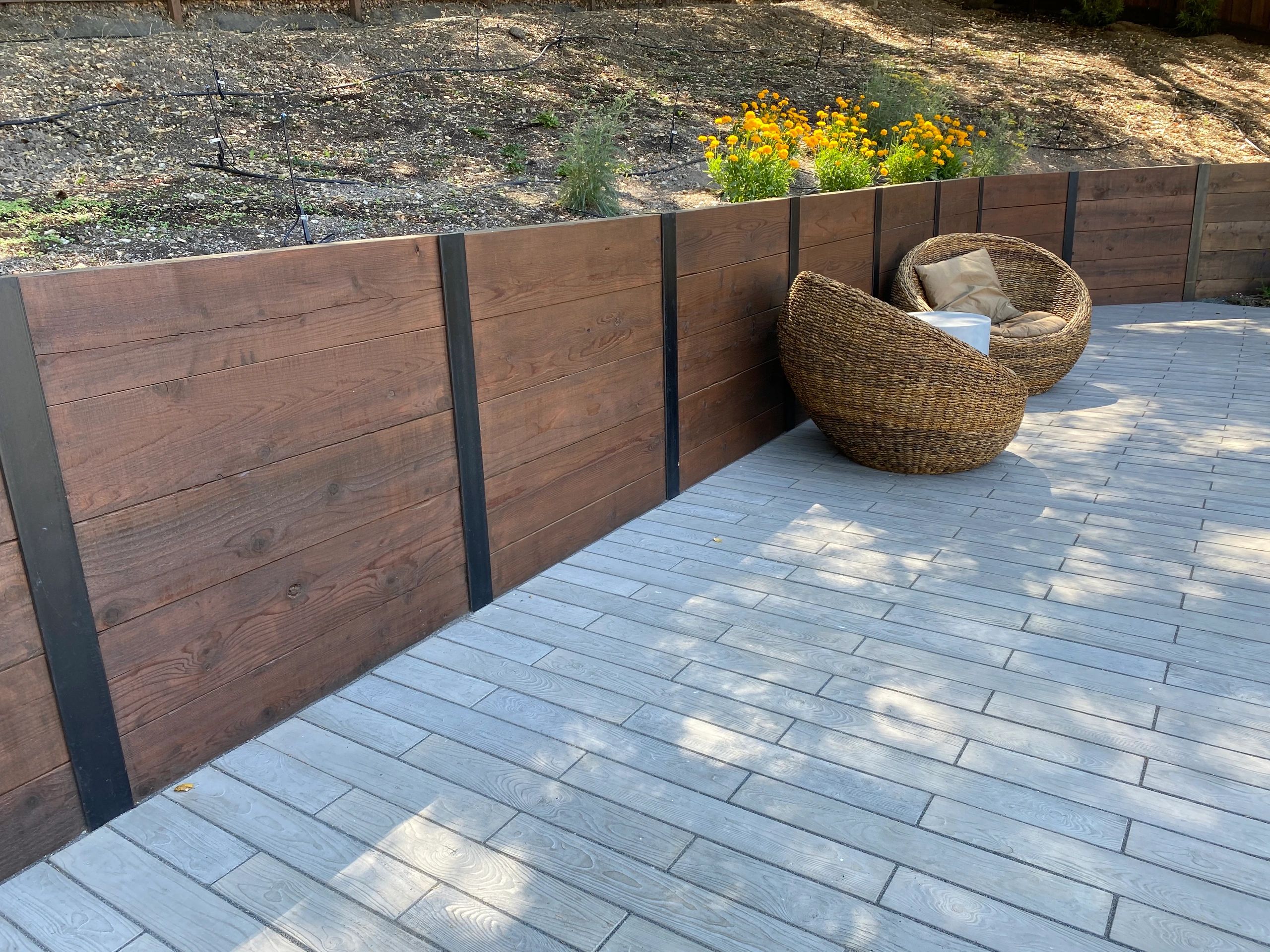 Wooden deck with wicker chairs and flowers.